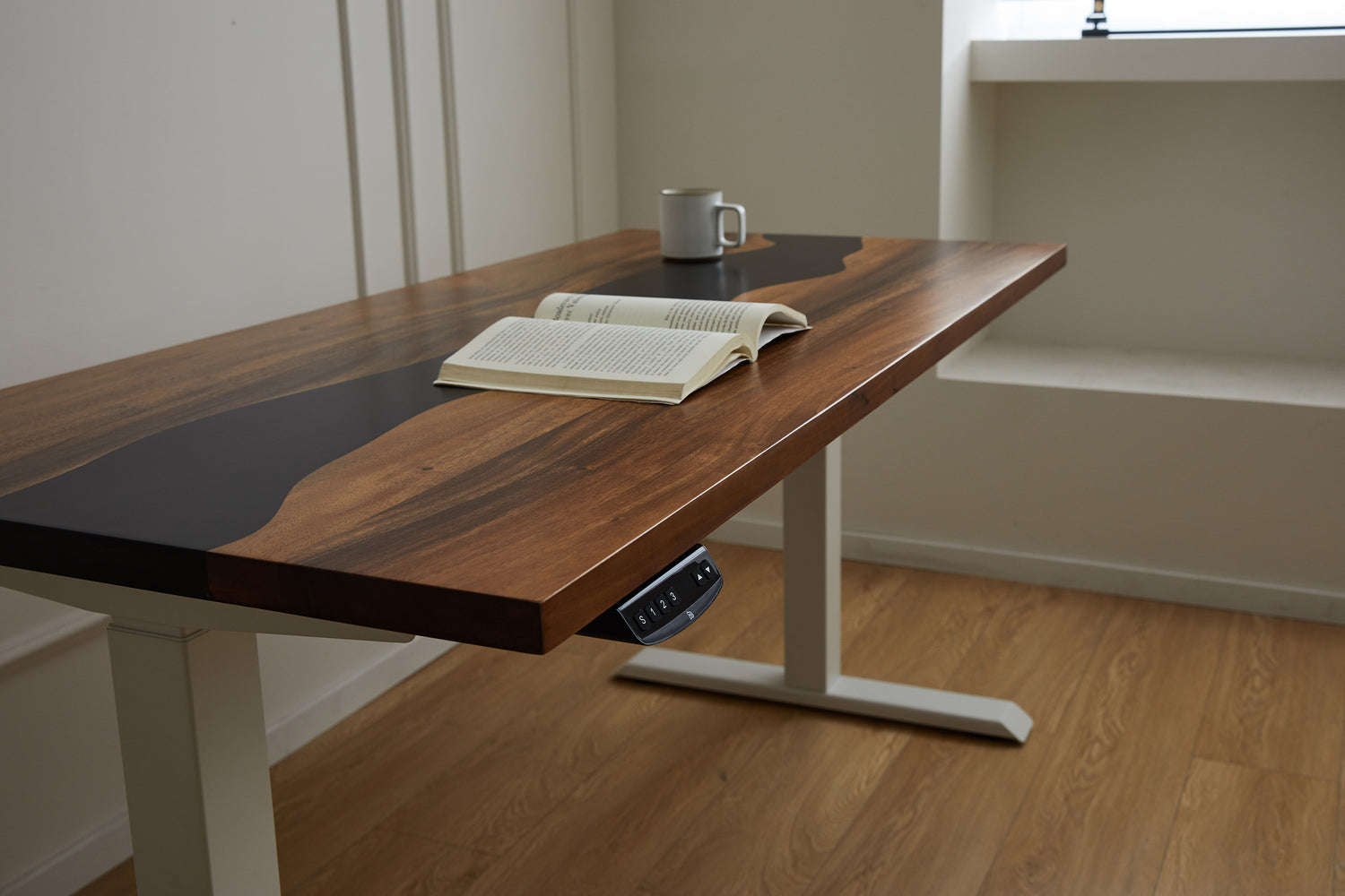 A scene view on a UK wood top with black epoxy inlay, with a book and a cup on the wood top surface.